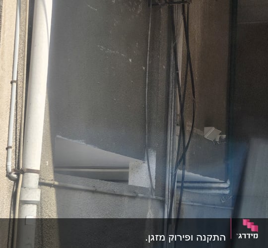 יחידת מזגן חיצונית מותקנת על קיר עם צינורות חשמל